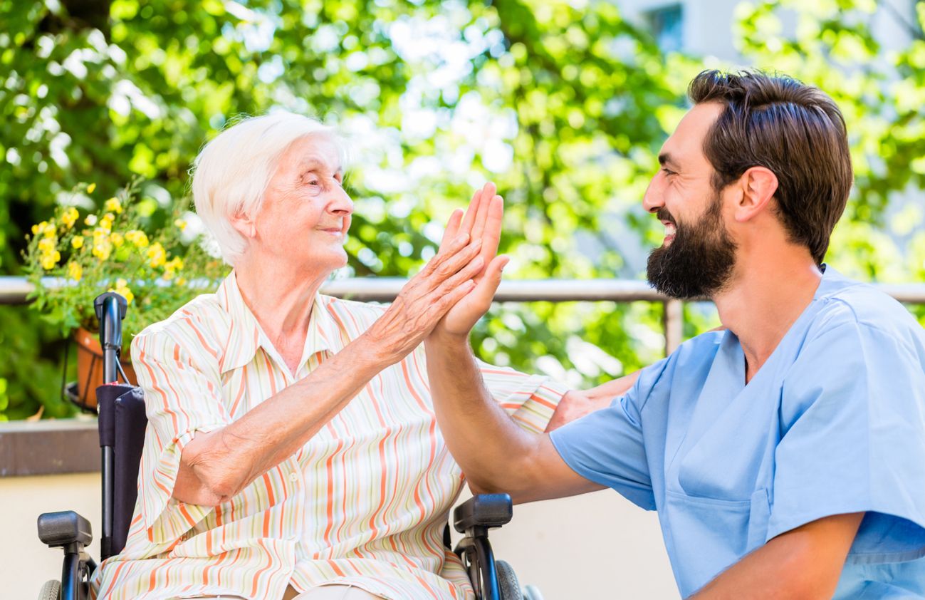 Ein Pfleger gibt einer älteren Frau einen High Five und zeigt Freude und Unterstützung.
